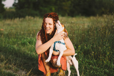 Beautiful woman plays with her jack russell dog in the park.