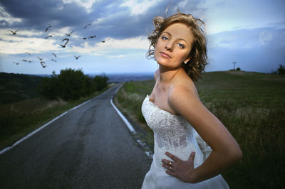 Portrait of beautiful young woman standing on road