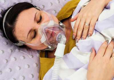 High angle view of woman with oxygen mask lying on bed