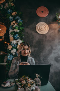 Young woman using mobile phone while standing on table
