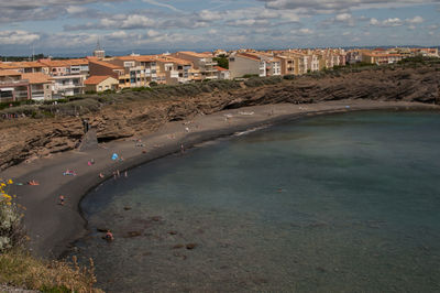 Buildings in town by sea against sky