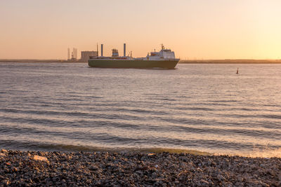 Ship sailing on sea against sky during sunset