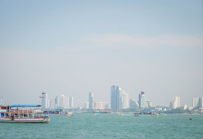 Boats in sea against buildings in city