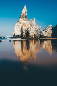 Reflection of built structure in water against clear sky