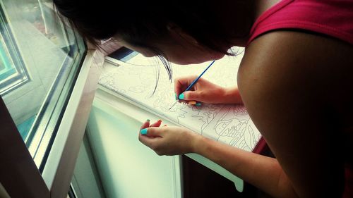 Close-up of woman painting on paper at table