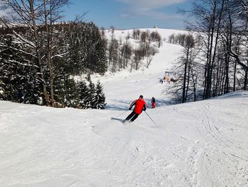 Man skiing on field against sky during winter