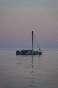 Sailboat sailing on sea against sky during sunset