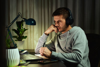 Side view of young woman using mobile phone at home