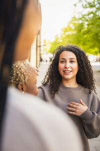 Young woman talking with female friends while spending weekend together