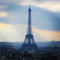 Communications tower in city against sky