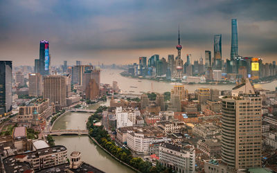 Aerial view of buildings in city against cloudy sky