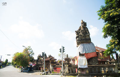 Statue amidst trees and buildings against sky