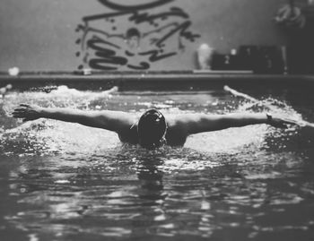 Male swimmer practicing butterfly strokes in swimming lane