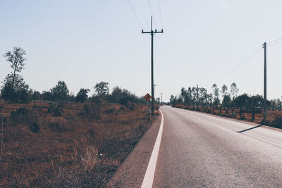 Road by trees against clear sky