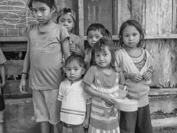 Portrait of siblings standing against wall