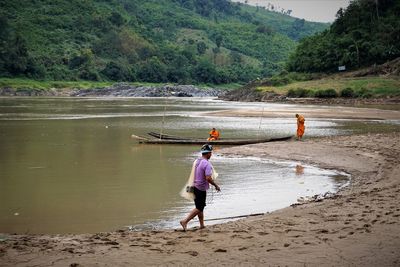 Side view of fisherman holding fishing net while walking on riverbank