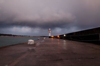 Lighthouse by sea against sky