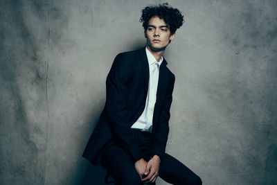 Young man sitting against wall