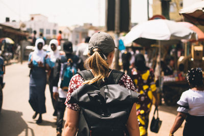 Rear view of people walking on city street