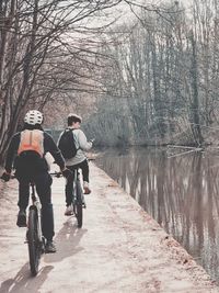 Rear view of people riding bicycle on water