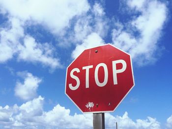 Low angle view of road sign against blue sky