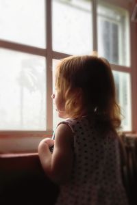 Rear view of girl looking through window