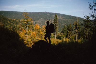 Silhouette man standing in forest against sky