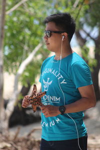 Young man with arms raised standing outdoors