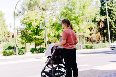 Side view of man riding push scooter on road