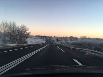 Road amidst trees against clear sky during winter