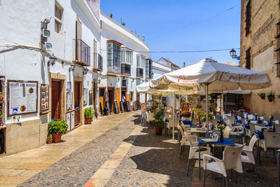 Chairs and tables on street amidst buildings in city