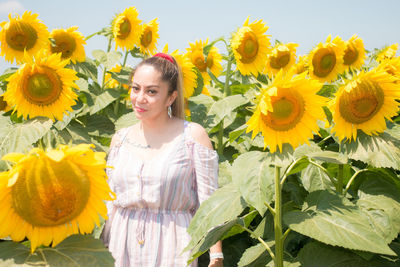 Portrait of smiling woman standing by sunflower