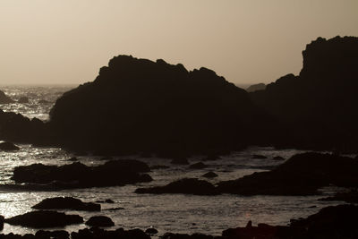 Scenic view of sea and silhouette mountains against clear sky