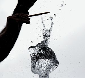 Close-up of hand holding water against white background