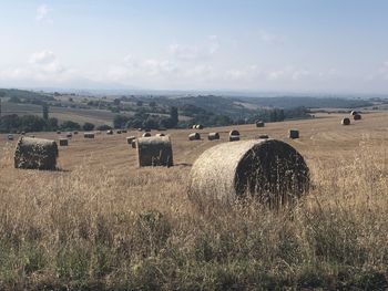 Hay bales on field against sky