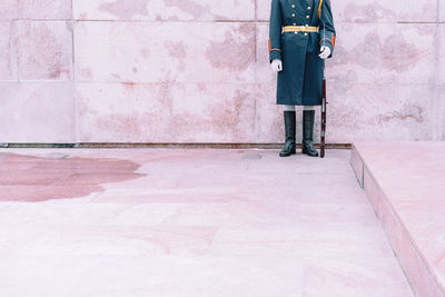 Low section of security guard standing by wall