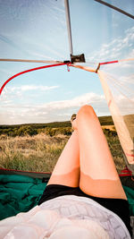 Low section of woman lying on land against sky