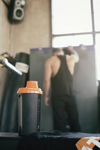 Close-up of bottle with man in background at gym