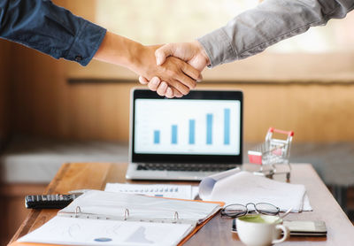 Close-up of businessmen shaking hands on table at office