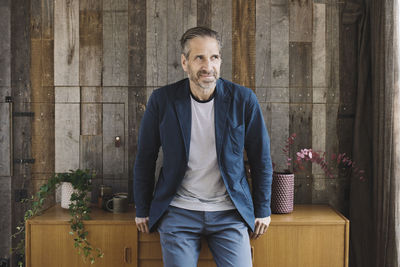 Thoughtful businessman leaning on sideboard against wood paneling in portable office truck