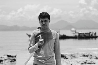 Portrait of man gesturing thumbs up at beach