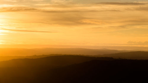 Scenic view of silhouette mountains against romantic sky at sunset