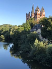 River amidst trees and buildings against clear sky