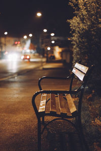 Empty chairs and table in city at night