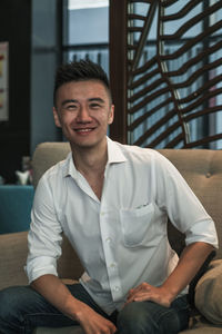 Portrait of young man sitting on sofa at home