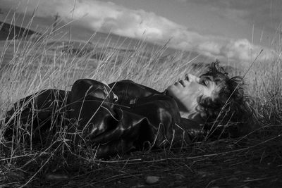 Young woman lying on field against sky