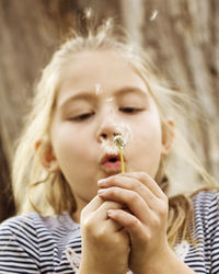 Close-up portrait of girl blowing dandelion