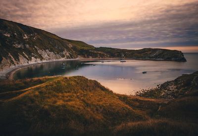 Scenic view of lulworth cove against sky during sunset