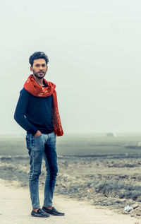 Portrait of young man wearing scarf standing on land