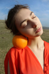 Close-up portrait of woman with orange fruit outdoors